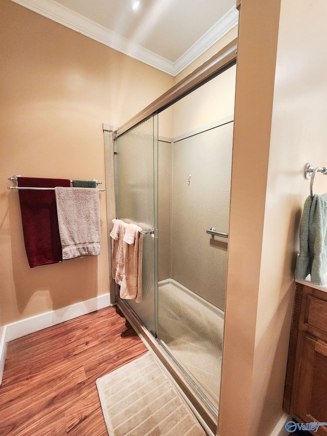 bathroom featuring hardwood / wood-style flooring, an enclosed shower, and ornamental molding