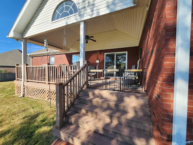 wooden deck featuring ceiling fan, a porch, and a yard