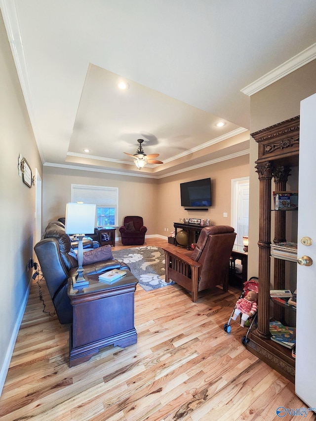 living room featuring ceiling fan, light hardwood / wood-style floors, and a tray ceiling