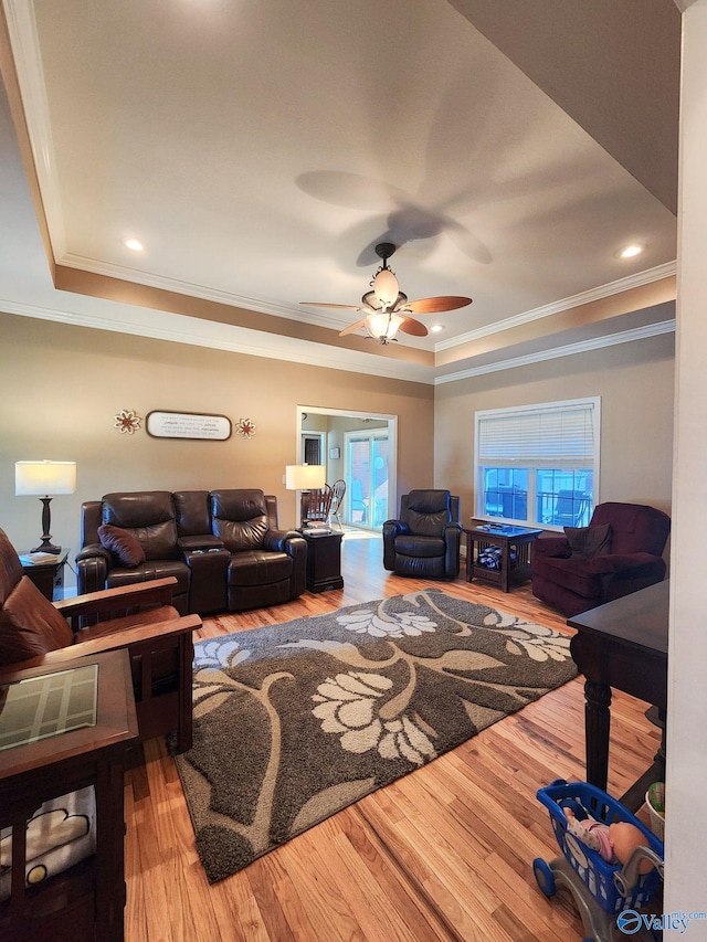 living room featuring a tray ceiling, ceiling fan, hardwood / wood-style floors, and ornamental molding