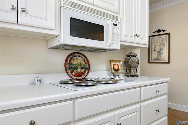 kitchen with hardwood / wood-style floors, white cabinetry, and ornamental molding