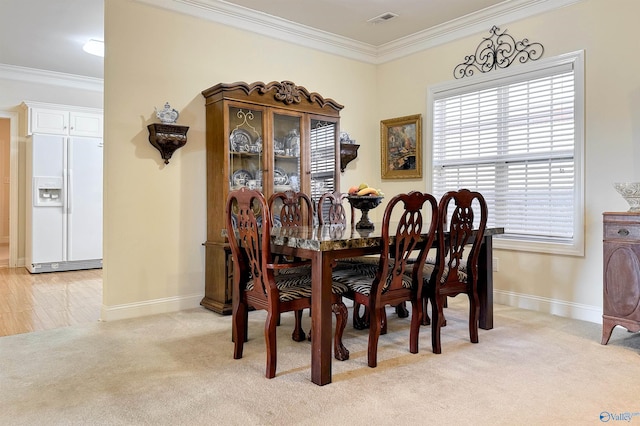 dining room with light colored carpet and crown molding