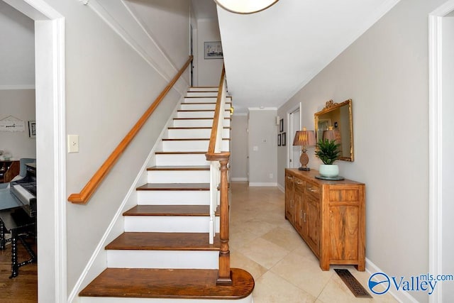 staircase with crown molding and tile patterned floors