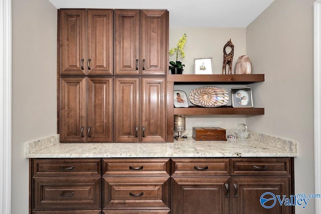 bar featuring light stone countertops and dark brown cabinetry