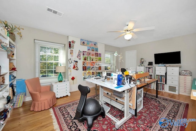 office area with ceiling fan with notable chandelier and light hardwood / wood-style floors