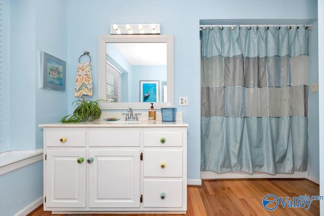 3318 Ohara Rd SW, Huntsville, AL 35801 - full bath with baseboards, shower / bathtub combination with curtain, wood finished floors, and vanity