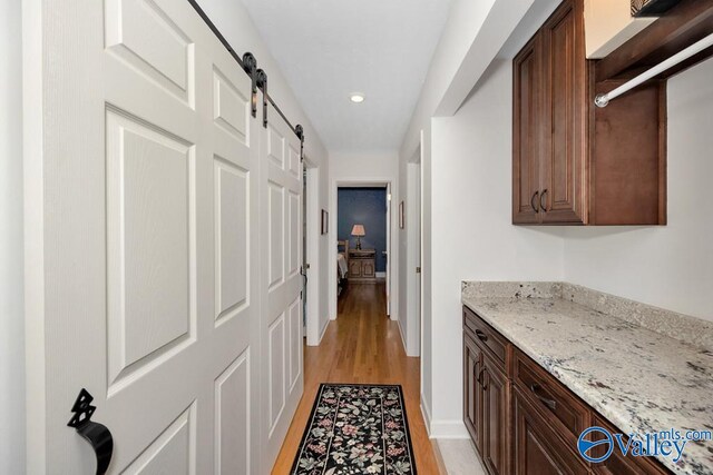 hall featuring a barn door and light hardwood / wood-style floors