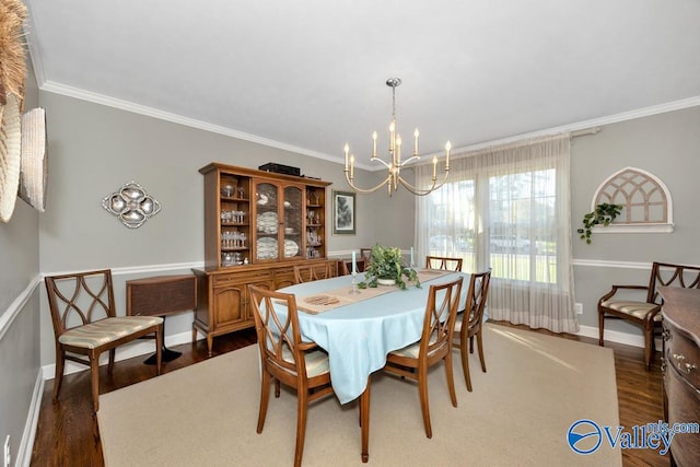 dining room with dark wood-type flooring, ornamental molding, and a notable chandelier