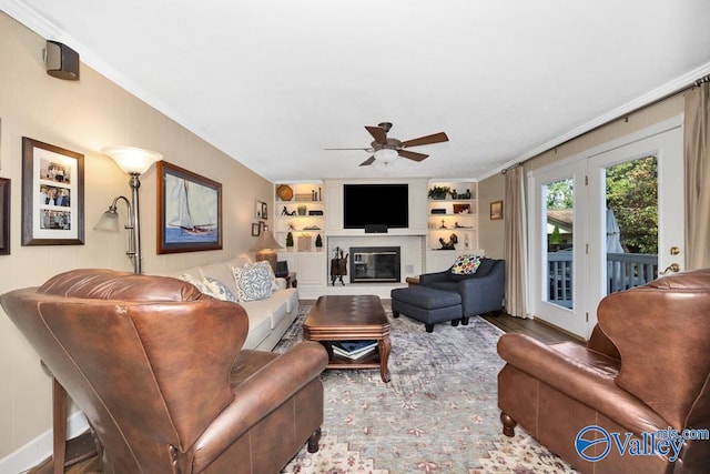 living room featuring built in features, crown molding, wood-type flooring, and ceiling fan