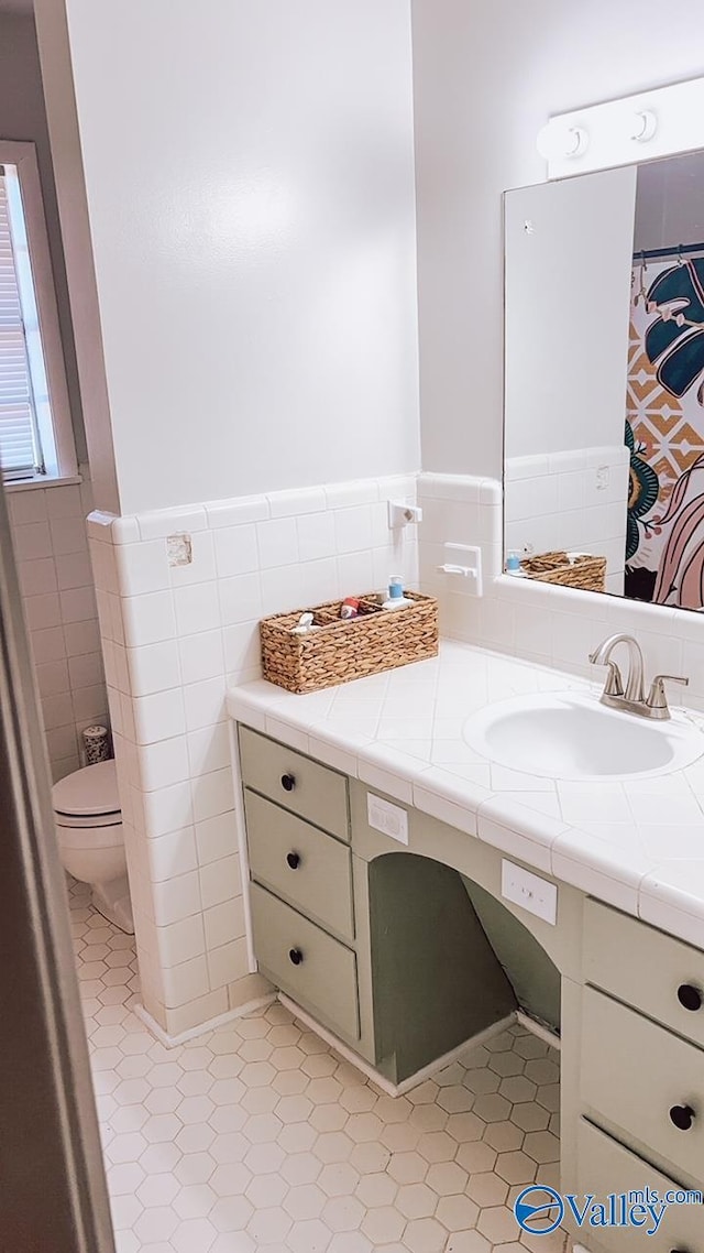 bathroom with vanity, tile walls, tile patterned floors, and toilet