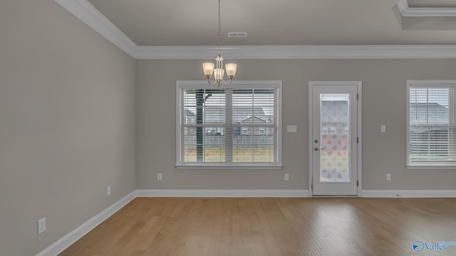 unfurnished dining area featuring an inviting chandelier, baseboards, ornamental molding, and light wood-style flooring