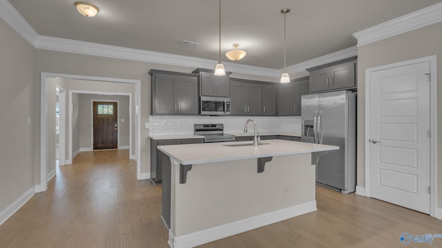 kitchen with a kitchen breakfast bar, light countertops, a sink, backsplash, and stainless steel appliances