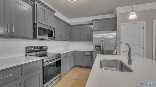 kitchen featuring crown molding, appliances with stainless steel finishes, a sink, light countertops, and gray cabinets