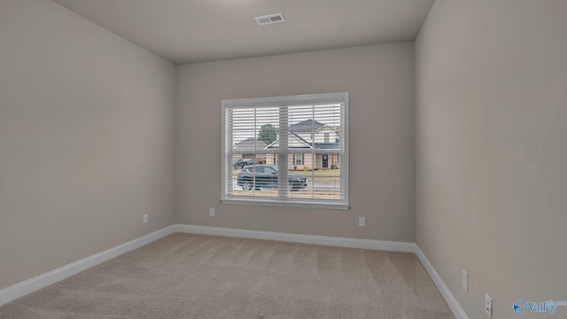 spare room with visible vents, baseboards, and light carpet