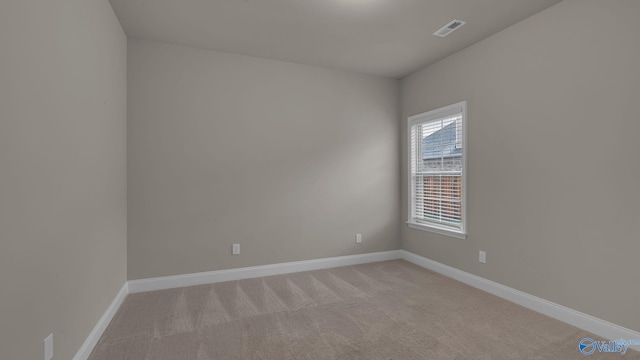 empty room with baseboards, light colored carpet, and visible vents