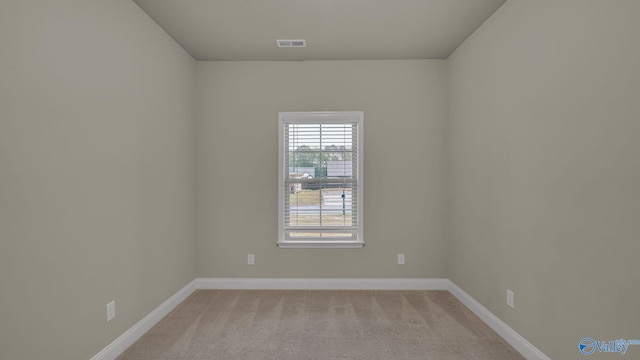 spare room featuring visible vents, baseboards, and light colored carpet