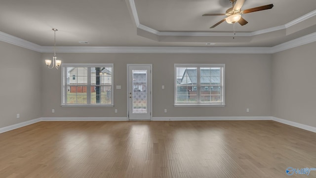 unfurnished room featuring a tray ceiling, plenty of natural light, wood finished floors, and ceiling fan with notable chandelier