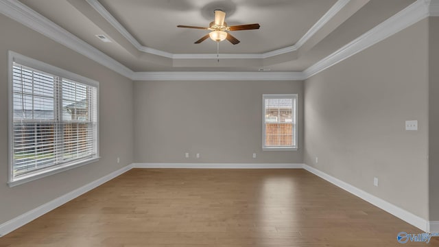 spare room featuring crown molding, ceiling fan, a raised ceiling, baseboards, and wood finished floors