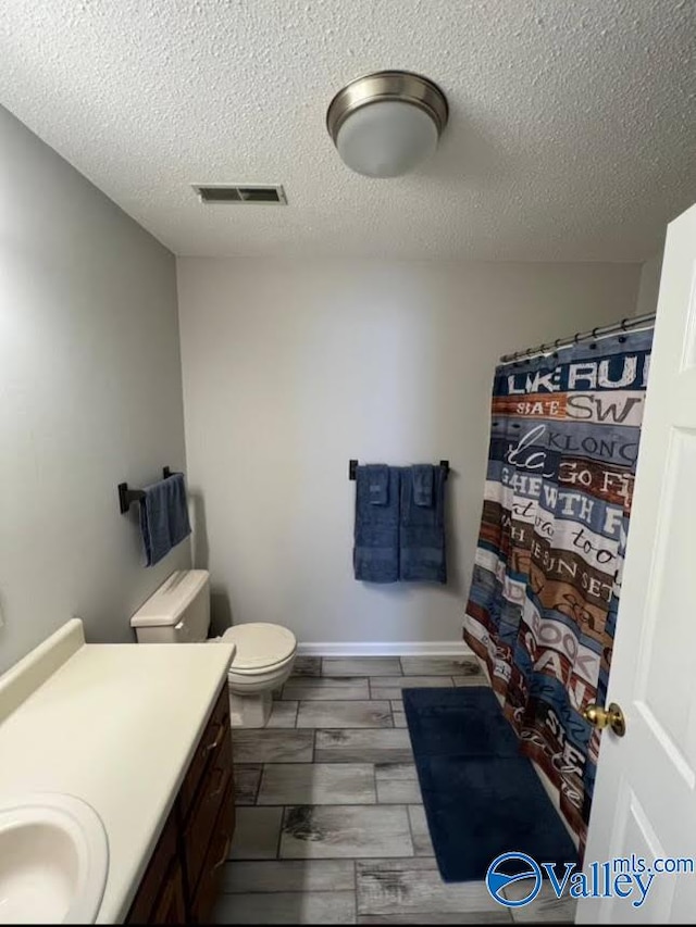 bathroom with toilet, hardwood / wood-style floors, vanity, a textured ceiling, and a shower with shower curtain