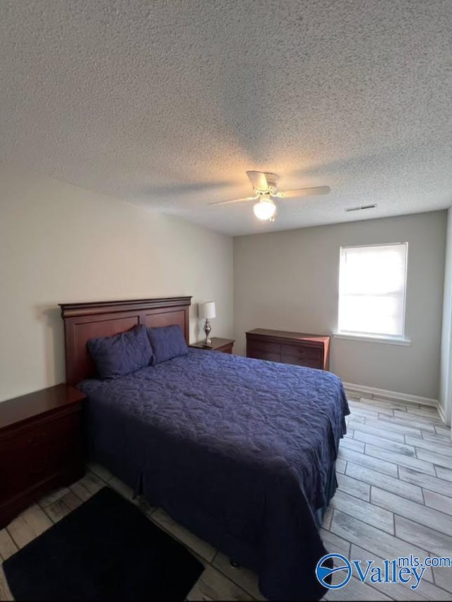 bedroom featuring a textured ceiling, light hardwood / wood-style flooring, and ceiling fan