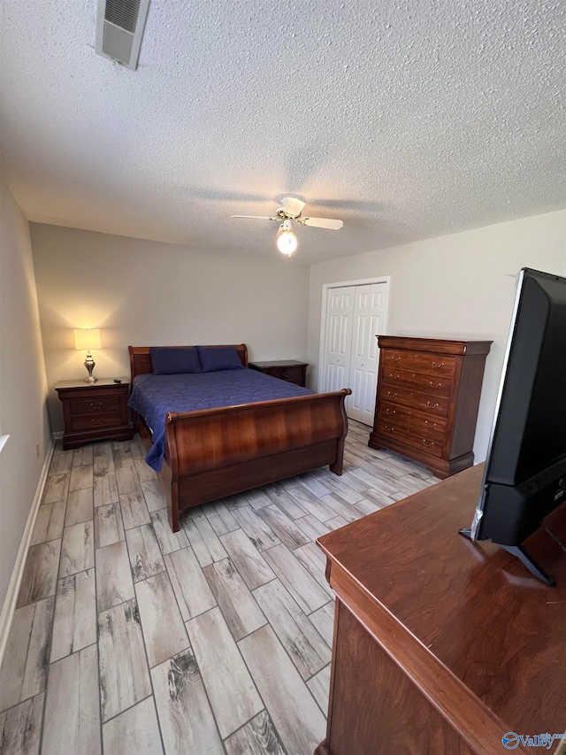 bedroom featuring light wood-type flooring, a closet, ceiling fan, and a textured ceiling