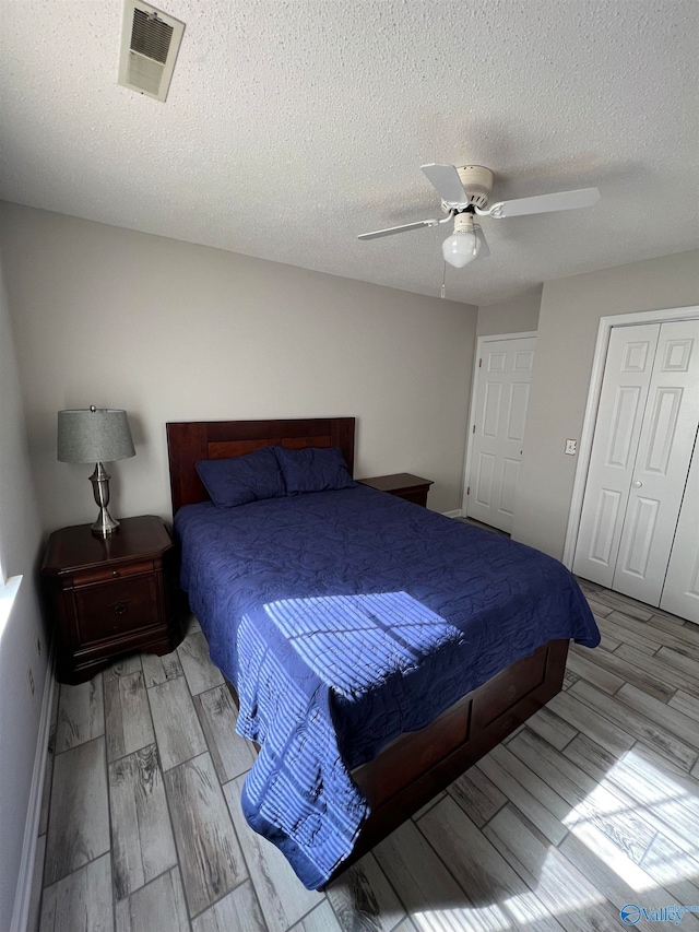 bedroom featuring light wood-type flooring, a closet, ceiling fan, and a textured ceiling