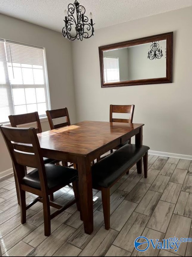 dining area featuring light wood-type flooring, an inviting chandelier, and a textured ceiling