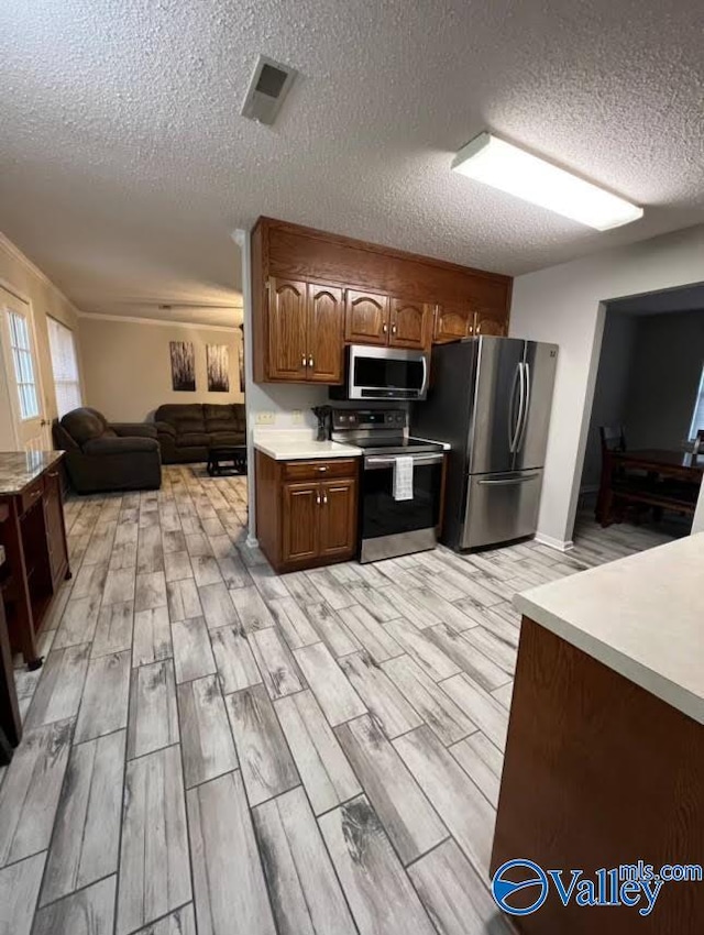 kitchen with a textured ceiling, light hardwood / wood-style flooring, and stainless steel appliances