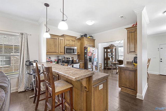 kitchen featuring dark wood-style flooring, ornamental molding, stainless steel appliances, baseboards, and a breakfast bar
