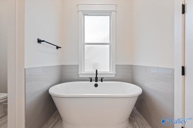 bathroom featuring a wealth of natural light, toilet, tile patterned floors, and tile walls