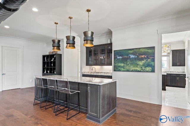 bar featuring dark brown cabinets, pendant lighting, light stone counters, and dark tile patterned floors