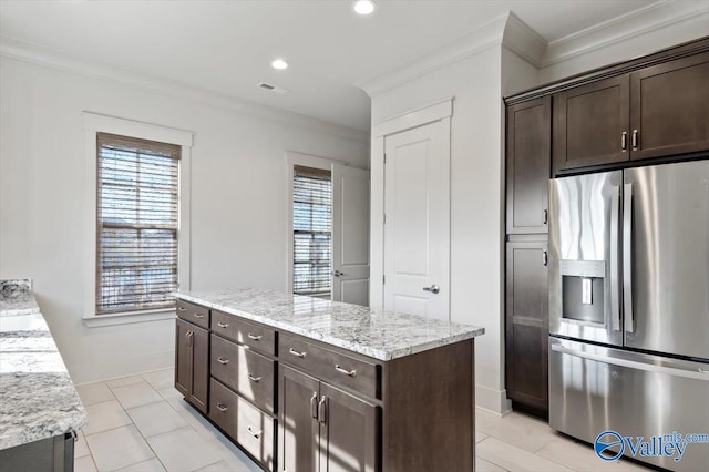 kitchen featuring a kitchen island, ornamental molding, light stone counters, light tile patterned floors, and stainless steel fridge