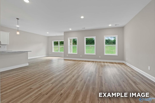 unfurnished living room with baseboards, light wood-type flooring, and recessed lighting