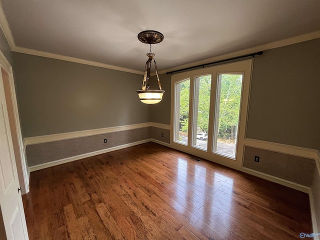 unfurnished room featuring baseboards, visible vents, ornamental molding, and wood finished floors