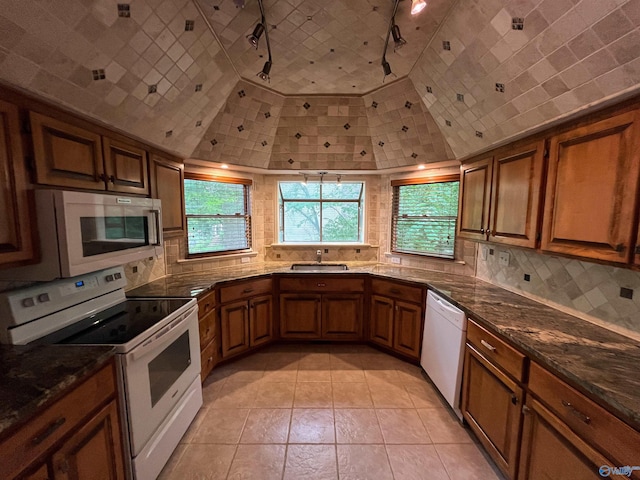 kitchen featuring white appliances, tasteful backsplash, brown cabinets, and a sink