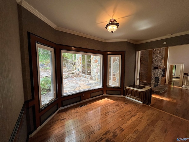 interior space with ornamental molding, wood-type flooring, visible vents, and a fireplace