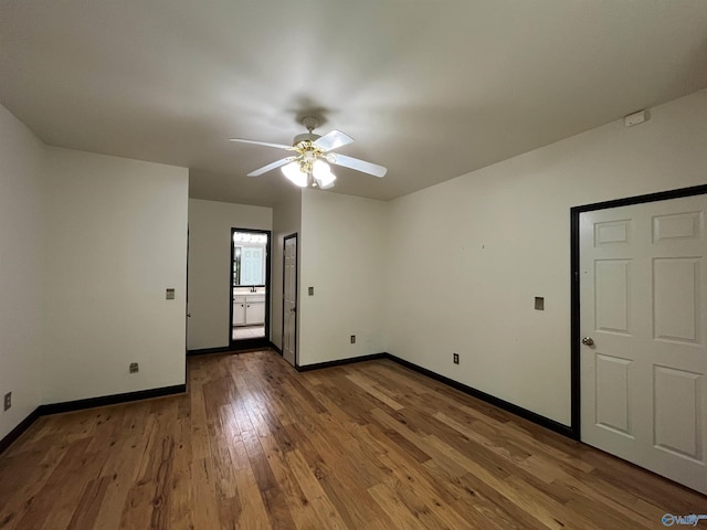 interior space featuring a ceiling fan, hardwood / wood-style flooring, and baseboards