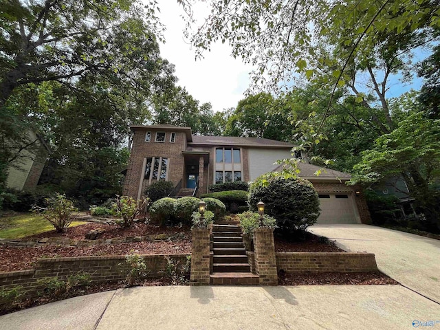 view of front of property with stairs, driveway, brick siding, and an attached garage