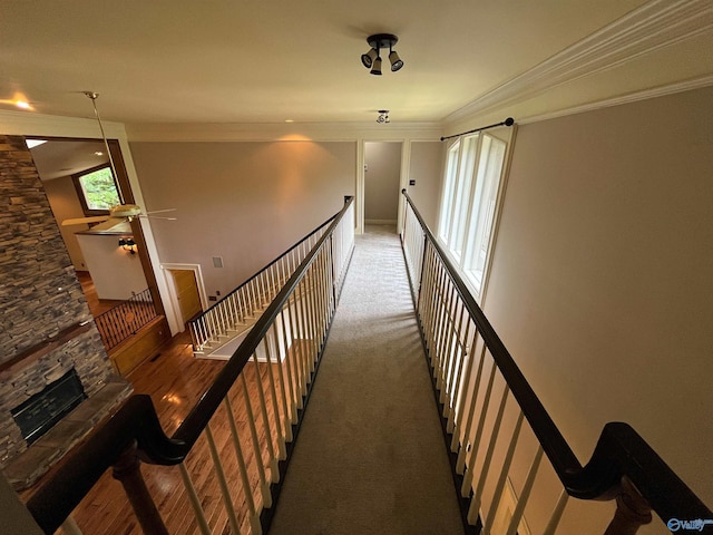 hall with ornamental molding, carpet floors, and an upstairs landing