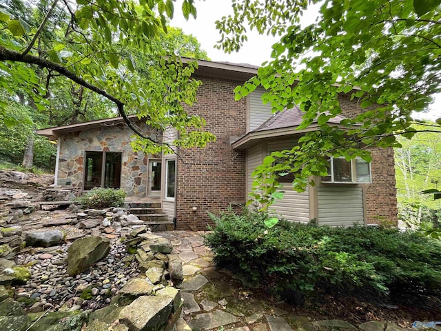 view of front of property with stone siding, a patio, and brick siding