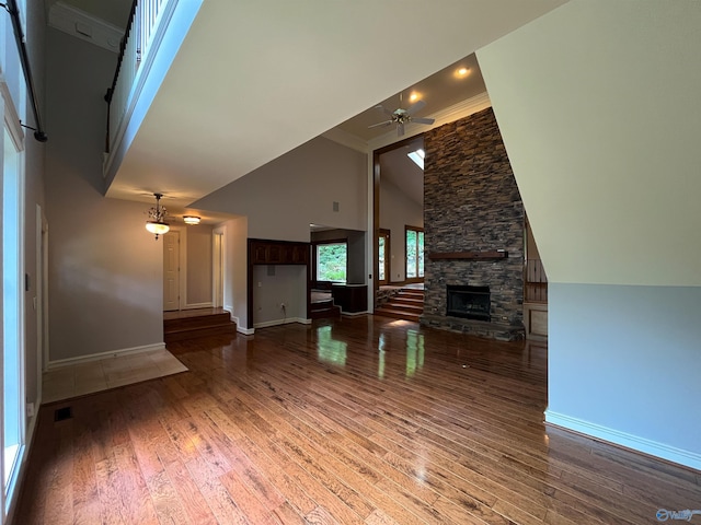 unfurnished living room featuring high vaulted ceiling, a stone fireplace, wood finished floors, a ceiling fan, and baseboards