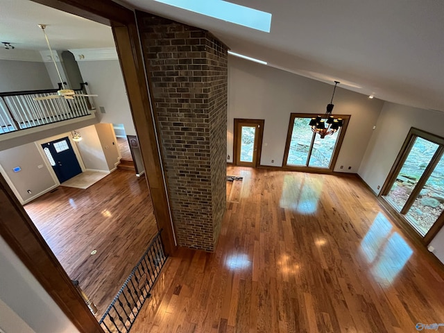 interior space with high vaulted ceiling, a skylight, hardwood / wood-style floors, and an inviting chandelier