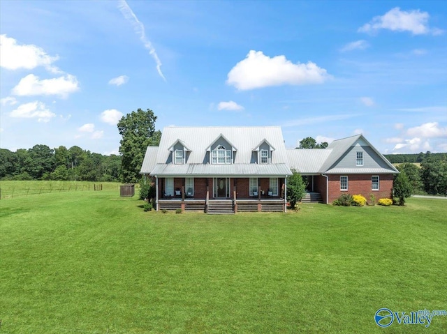 view of front of home with a front yard, brick siding, covered porch, and metal roof