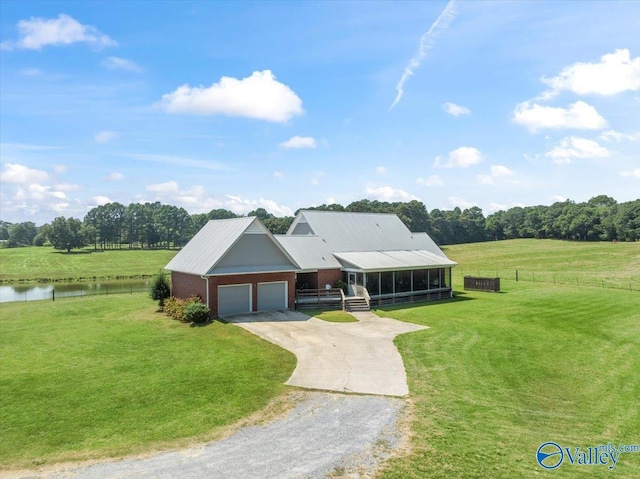 view of front of property featuring concrete driveway, an attached garage, a front yard, and a water view