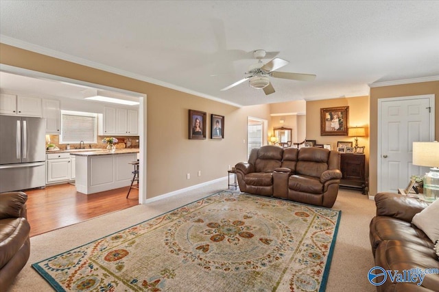 living area with crown molding, baseboards, a wealth of natural light, and ceiling fan