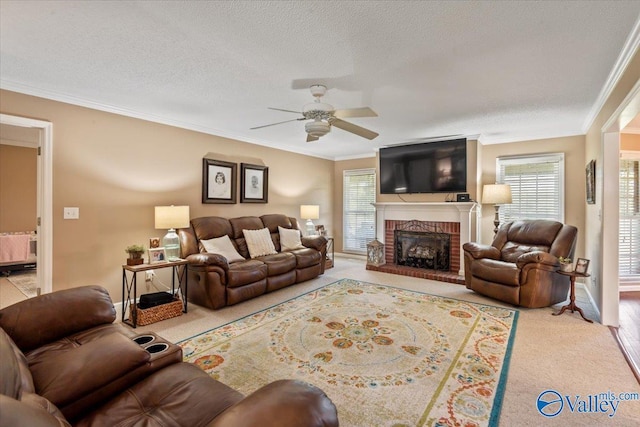 carpeted living room with plenty of natural light, a fireplace, a ceiling fan, and ornamental molding