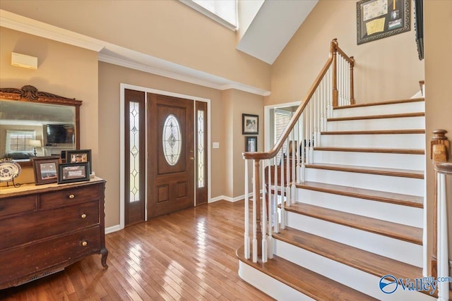 entryway with baseboards, crown molding, stairs, and hardwood / wood-style flooring