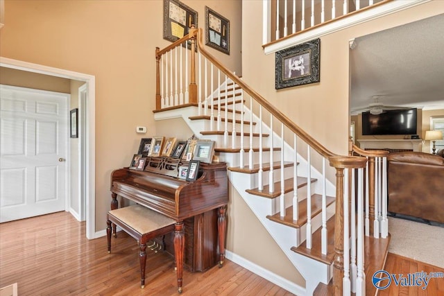 stairs featuring baseboards, a high ceiling, and wood finished floors