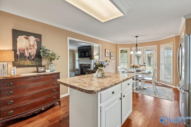 kitchen with dark wood-style floors, a fireplace, white cabinetry, and freestanding refrigerator