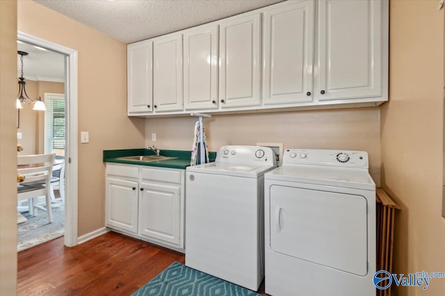 clothes washing area with washing machine and clothes dryer, a sink, cabinet space, a textured ceiling, and dark wood-style flooring